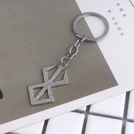 Berserk Game Logo Keychain - Show off your love for the iconic anime and game series with our officially licensed PS4 keychain. Made from durable metal, this keychain features the iconic Berserk logo and sword design, perfect for any fan to add to their collection. Order now and add a touch of anime style to your everyday life!